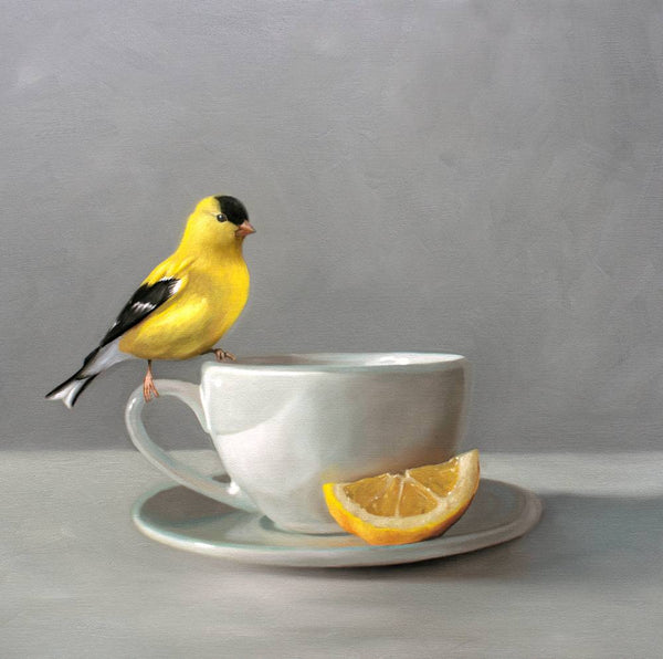 Goldfinch perched on a white teacup with a slice of lemon on a gray background