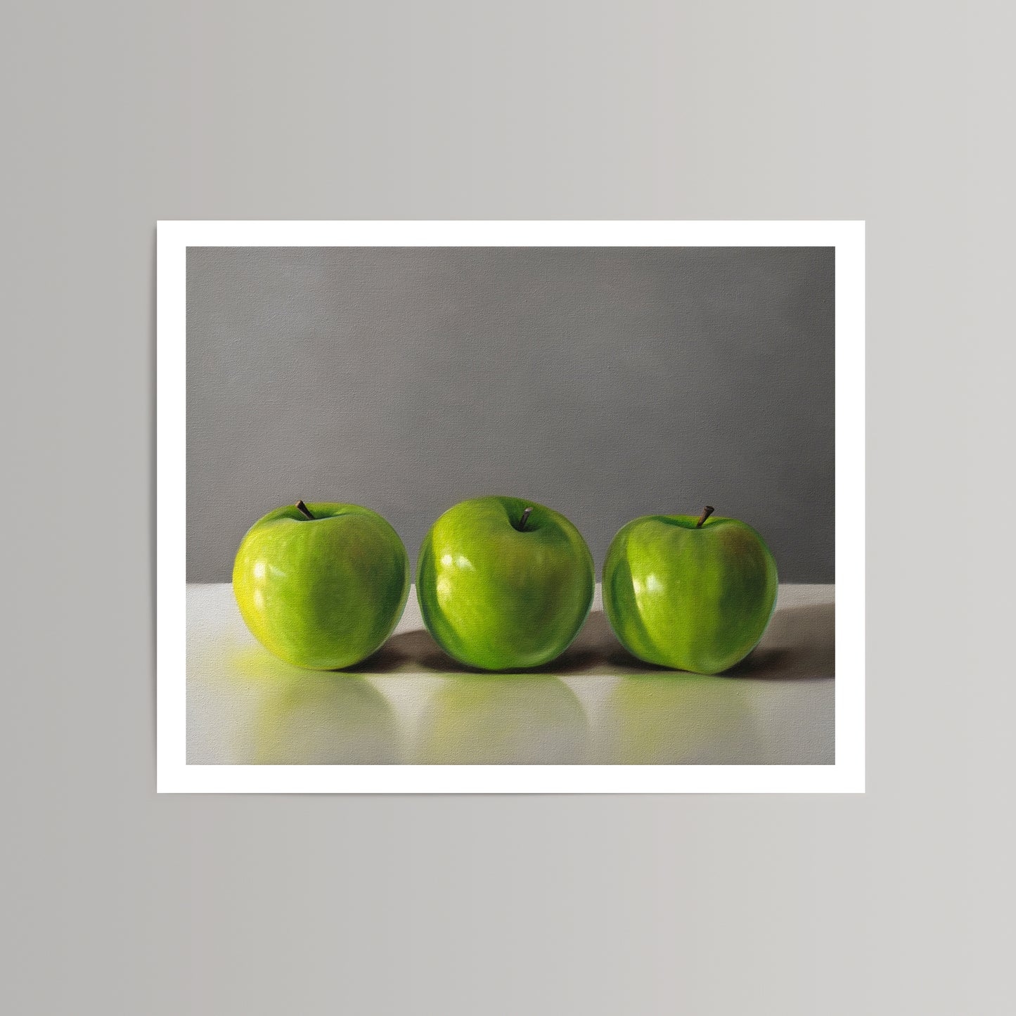 Fine art print of three vibrant green apples on a light surface against a gray background.