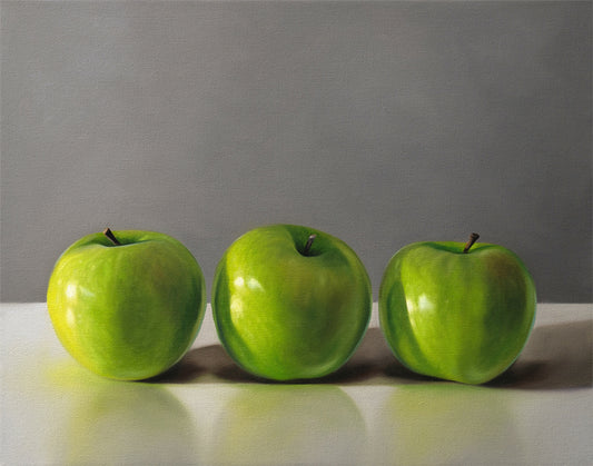 Fine art print of three vibrant green apples on a white surface against a gray background.