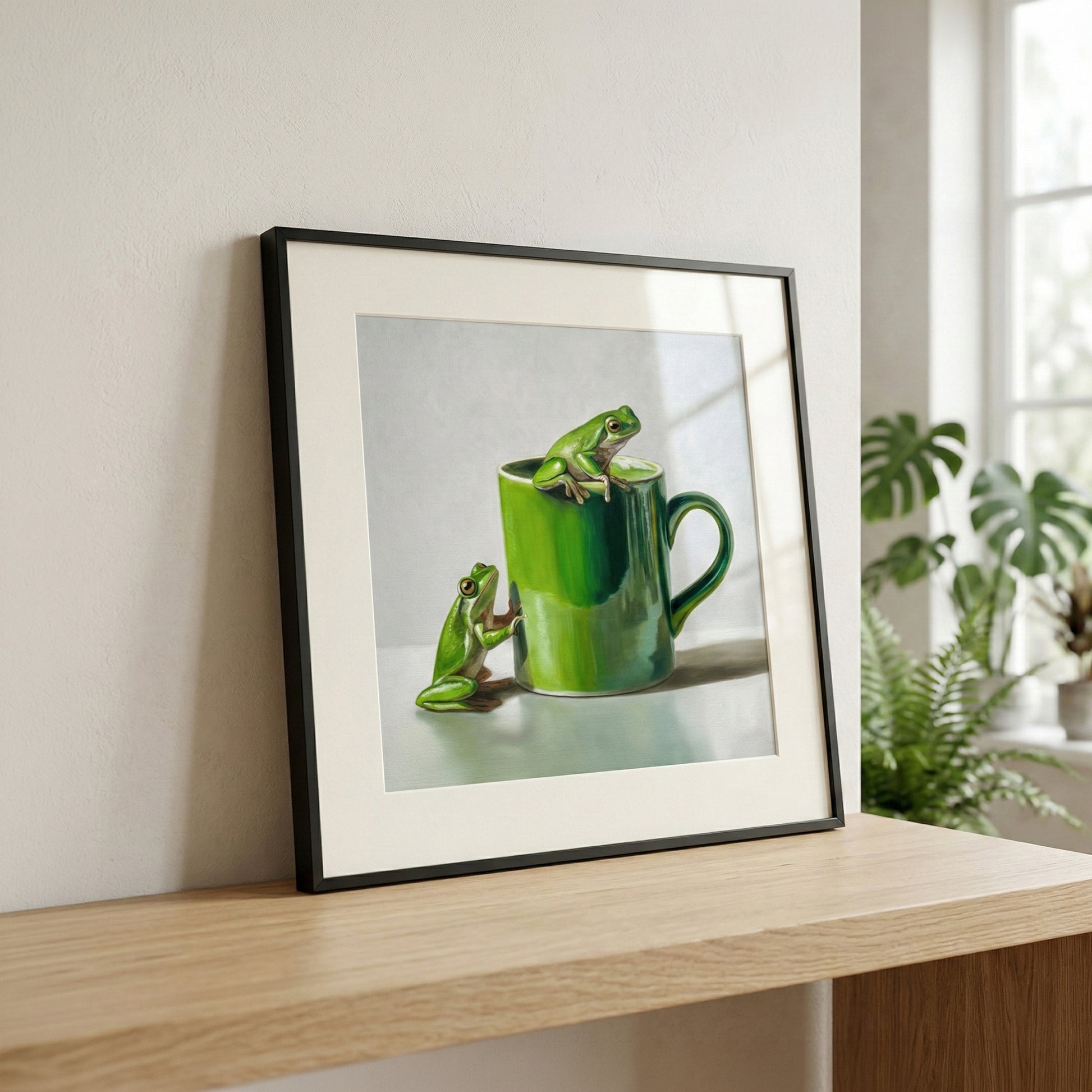 Framed fine art print of two vibrant green tree frogs with a matching green mug on a light background.