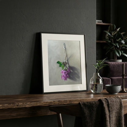 Framed fine art print of vibrant purple lilac blossoms hanging, displayed on a rustic wooden table.