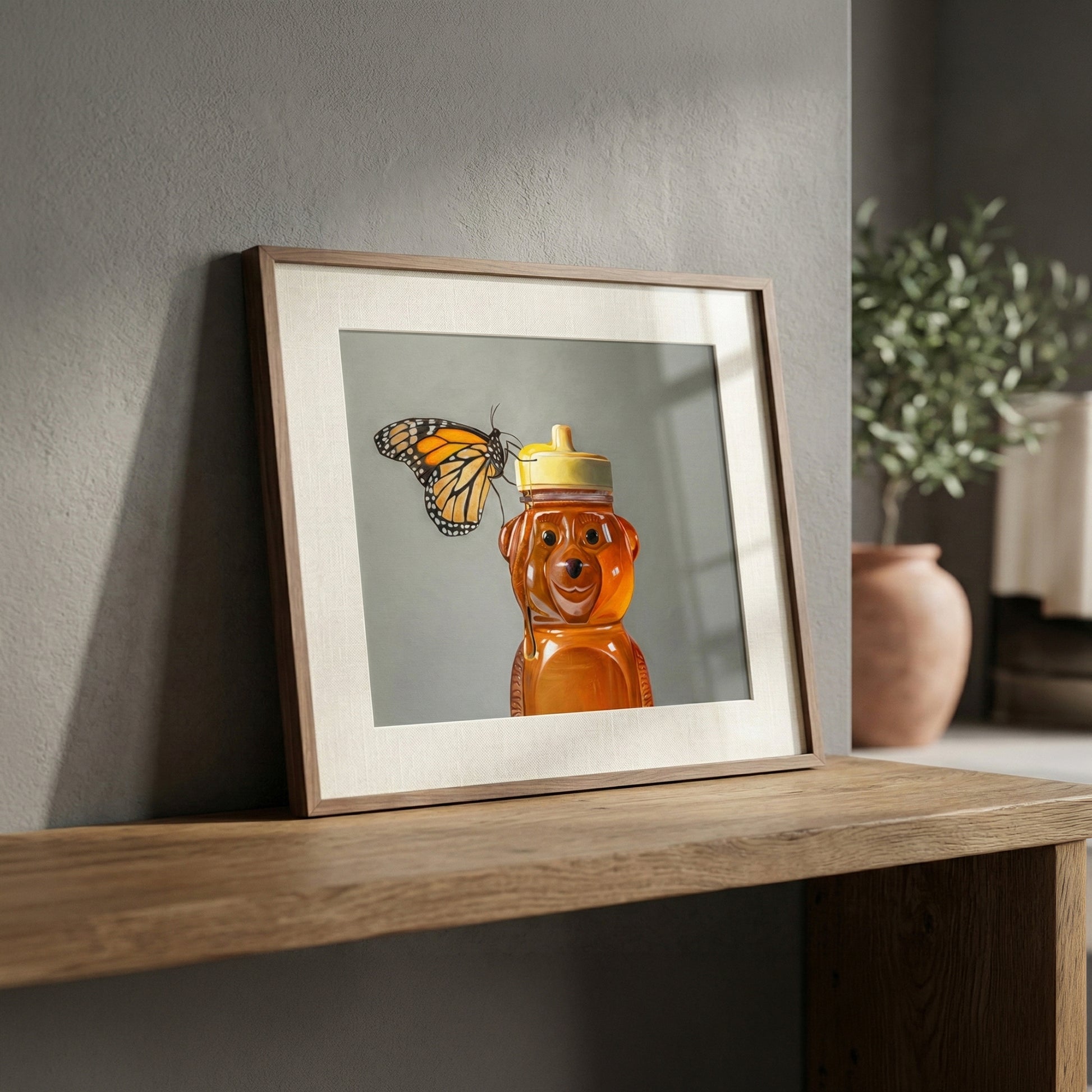 Framed fine art print of a monarch butterfly resting on a honey bear bottle, on a wooden shelf.