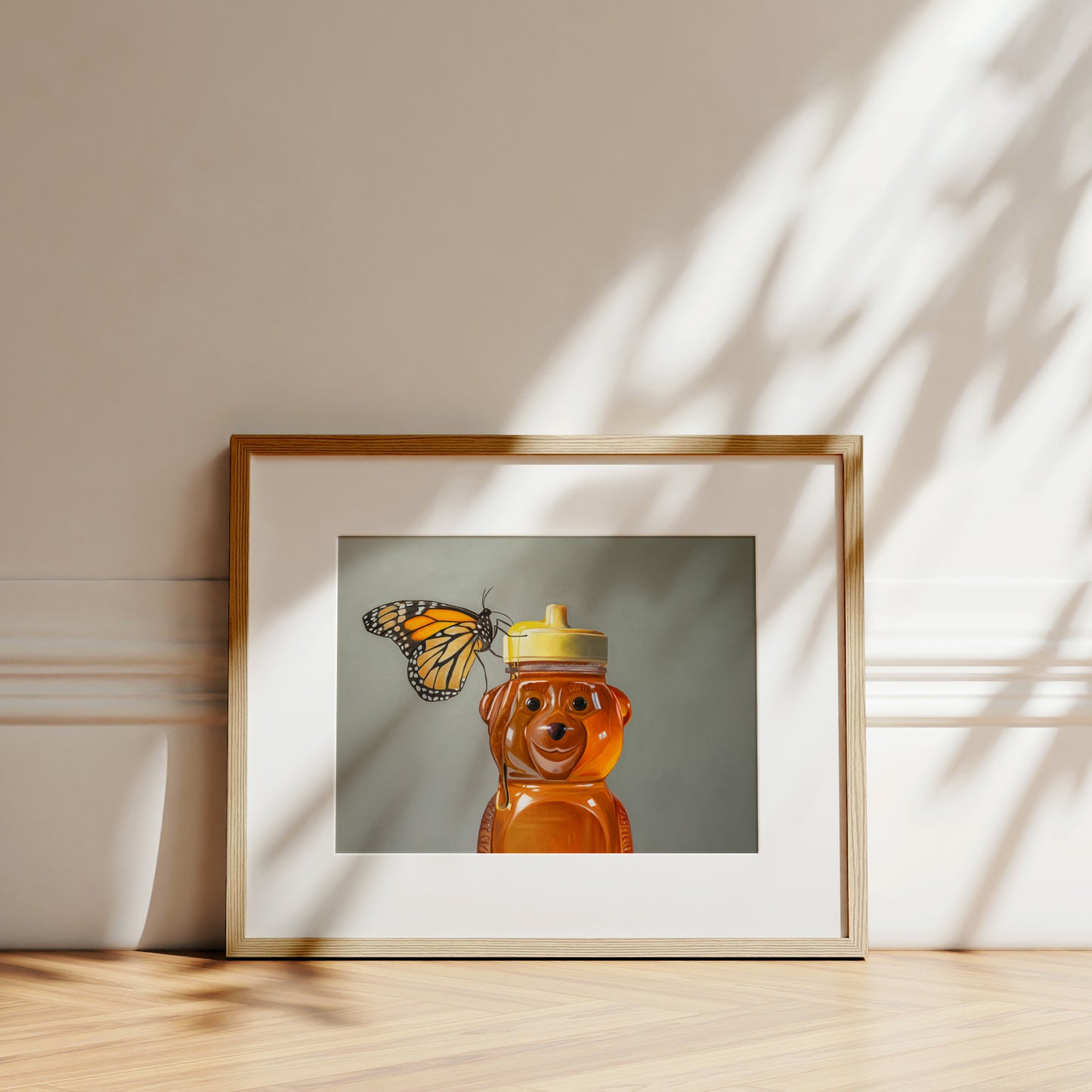 Framed fine art print of a monarch butterfly on a honey bear bottle, with sunlight shadows.