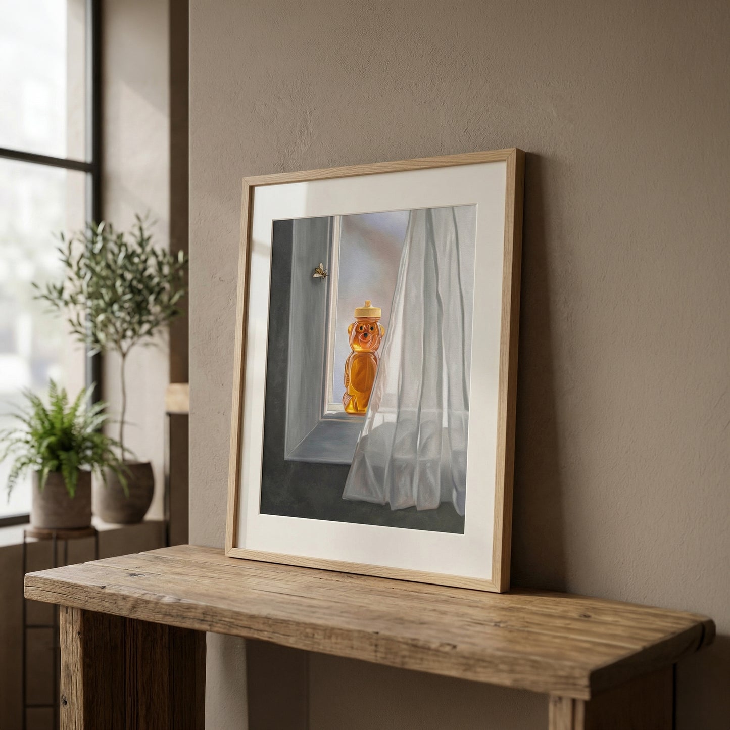Framed fine art print of a honey bear bottle and bee by a window with white curtains, on a wooden table.