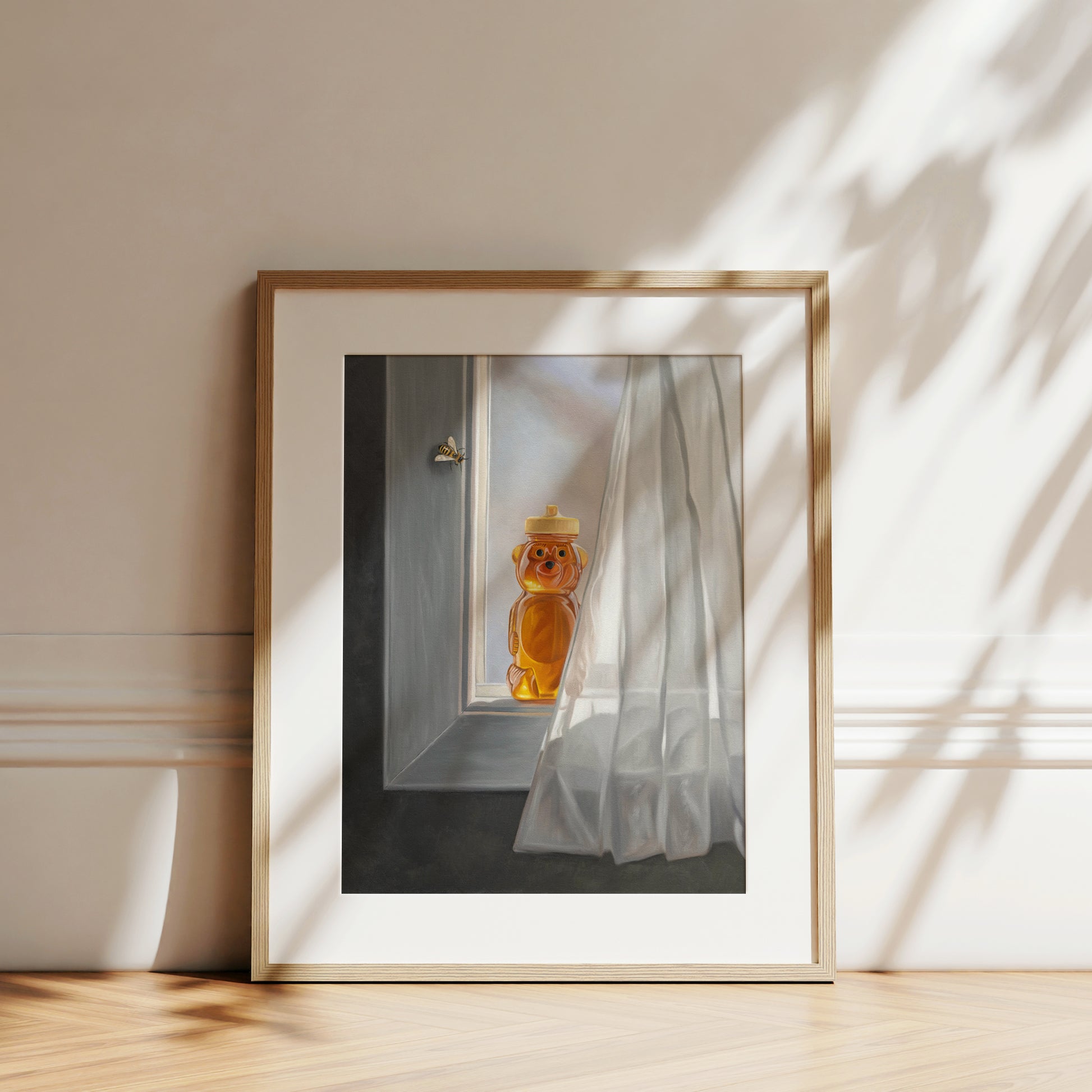 Framed fine art print of a honey bear jar and bee on a sunlit window sill with sheer white curtains.