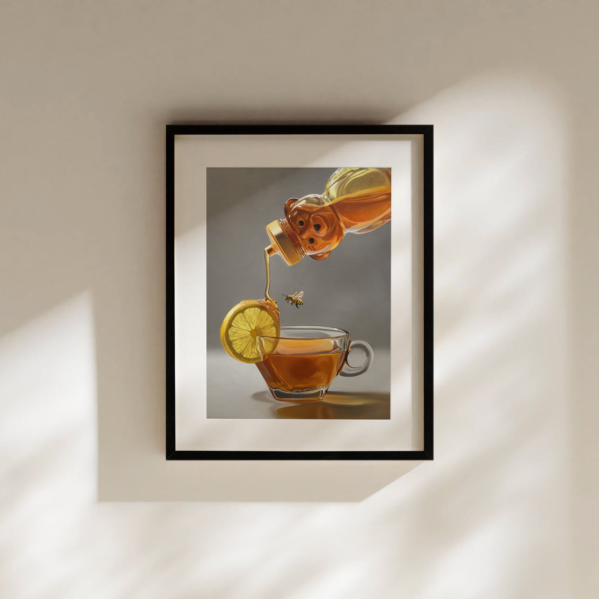 Framed fine art print of honey pouring into a tea cup with a lemon slice and bee.