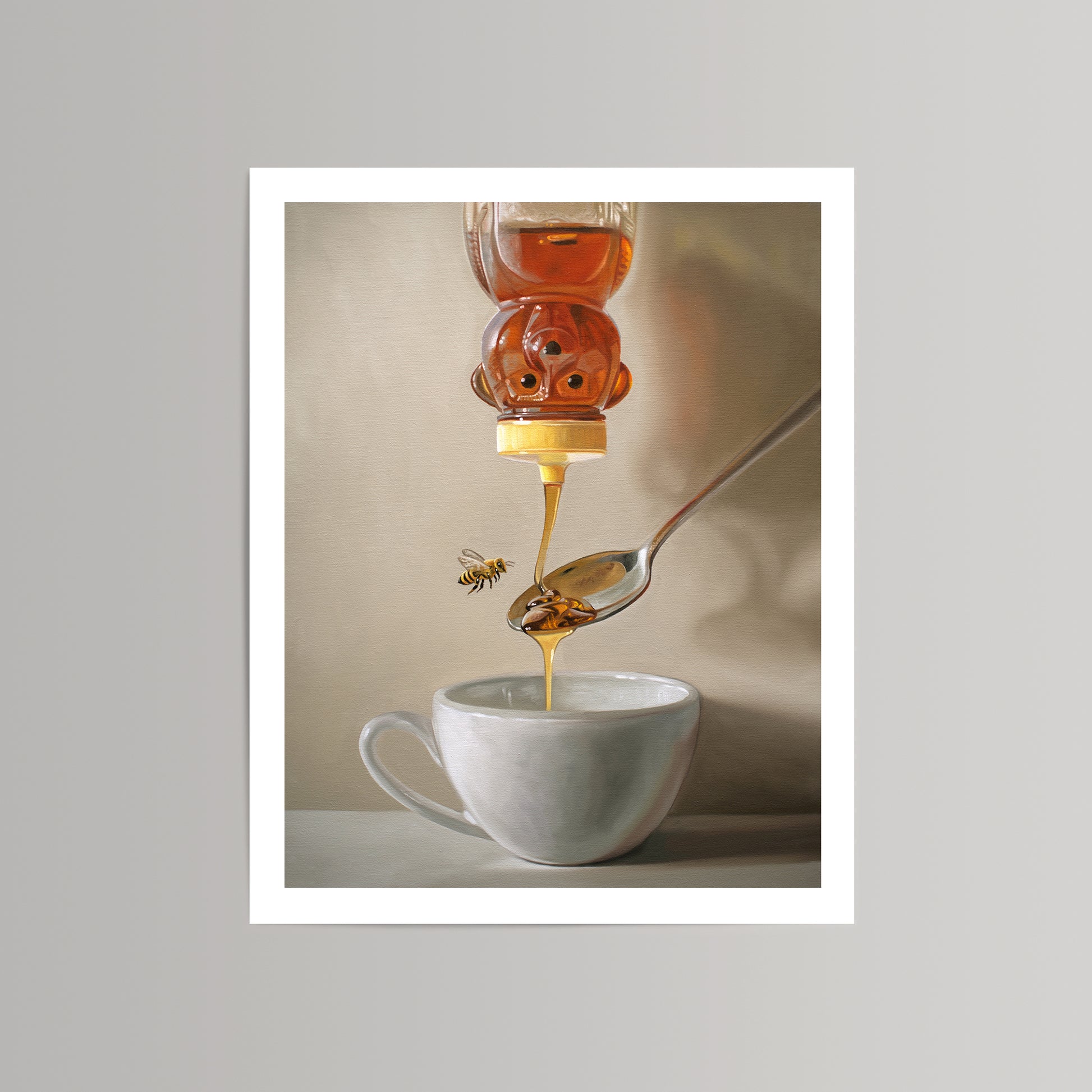 Fine art print of a honey bear bottle pouring golden honey onto a spoon, with a bee flying nearby a white teacup.
