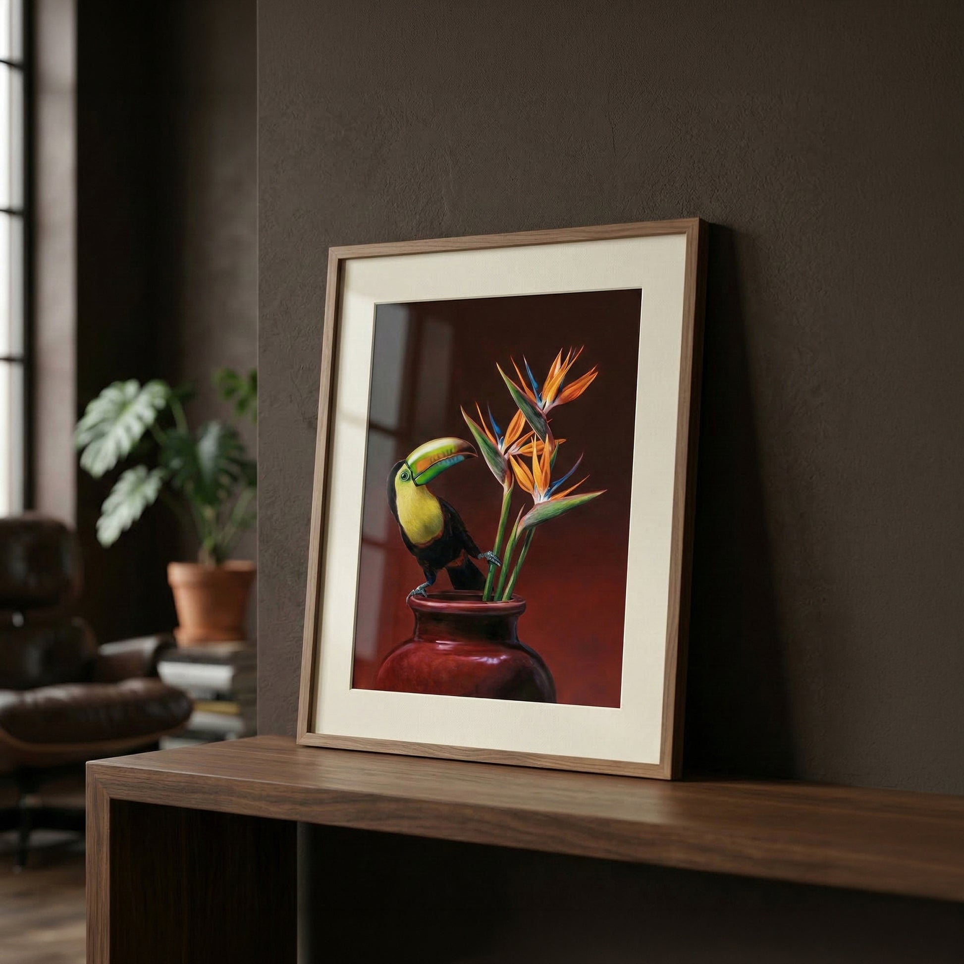 Vibrant Keel-billed Toucan and Bird of Paradise art print in a light wood frame with a cream mat, displayed on a dark wood surface.