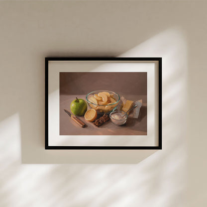 Oil painting print of apple pie ingredients including apples, cinnamon, and butter in a black frame on a beige wall.
