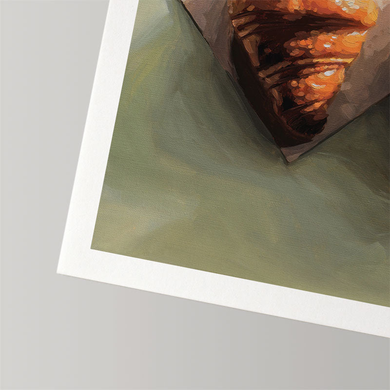 Fine art print of a golden croissant on a sage green background, featuring a textured white border on cotton rag paper.