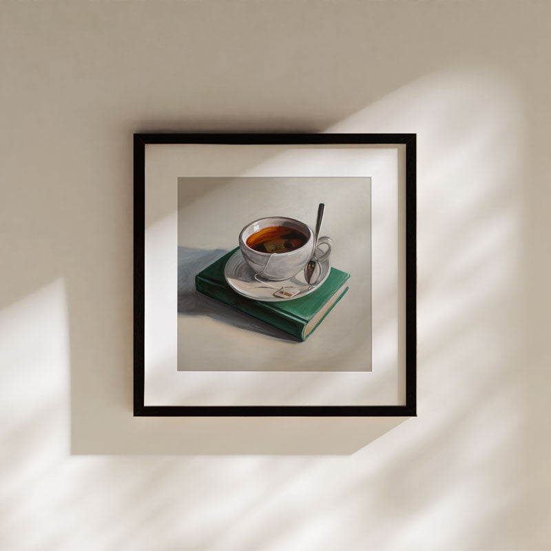 Framed fine art print of a white teacup on a green book, featuring archival pigment ink on cotton rag paper.