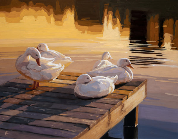 Four white ducks on a wooden dock by a body of water with a warm glow