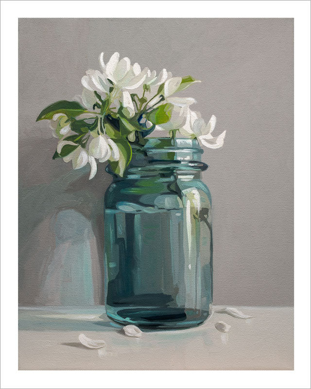 Fine art print of white apple blossoms in a blue glass mason jar on a grey background with a white border.