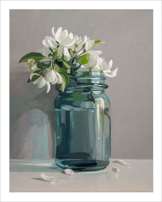 Fine art print of white apple blossoms in a blue glass mason jar on a grey background with a white border.