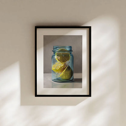 Fine art print of bright yellow lemons in a blue glass Ball mason jar, framed in black with a white mat border.