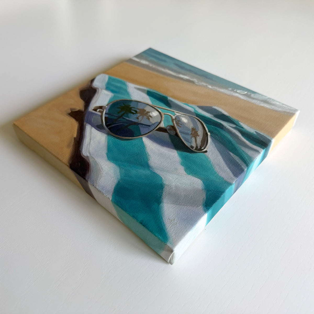 8x8 inch oil painting of aviator sunglasses on a blue and white striped beach towel with palm tree reflections.