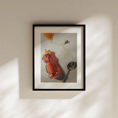 Fine art print of a honey bear bottle, spoon, and bee in a black frame on a neutral wall with soft sunlight.