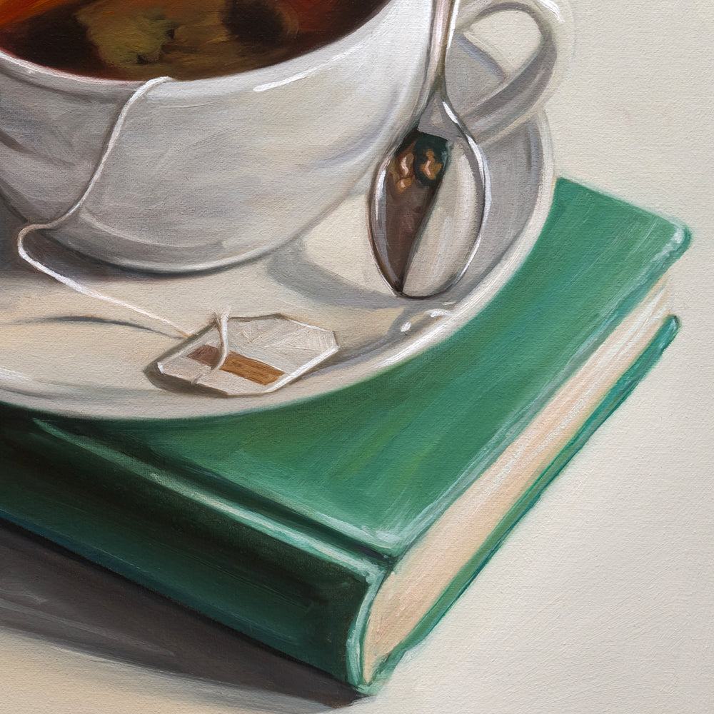 Teacup with saucer and teabag on a green book