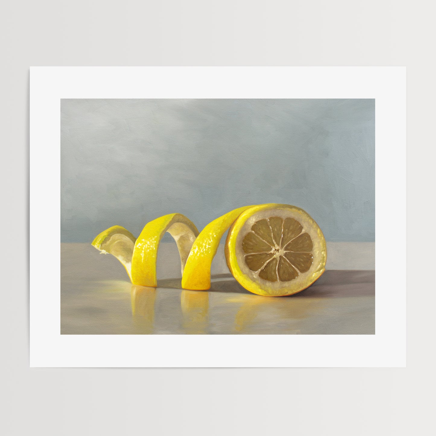 Lemon Twist Fine Art Print by Lauren Pretorius: a lemon half with its peeling spiraling out towards the left on a light, reflective surface and muted blue background.