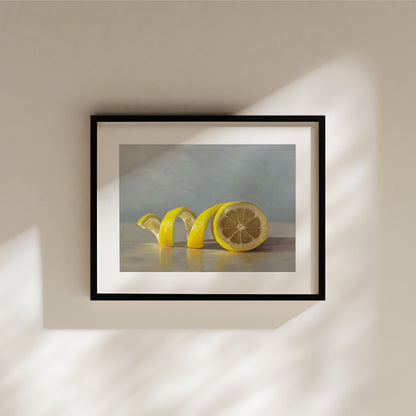 Lemon Twist Fine Art Print by Lauren Pretorius: a lemon half with its peeling spiraling out towards the left on a light, reflective surface and muted blue background.