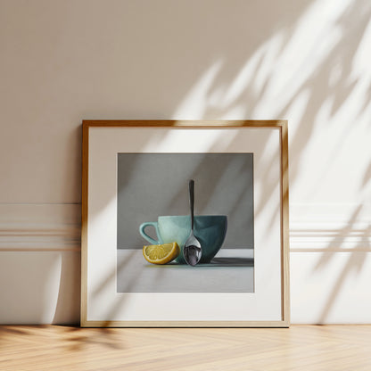 Framed fine art print of a still life with a teal cup, silver spoon, and yellow lemon wedge.
