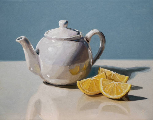 White ceramic teapot with lemon slices on a reflective surface against a blue background