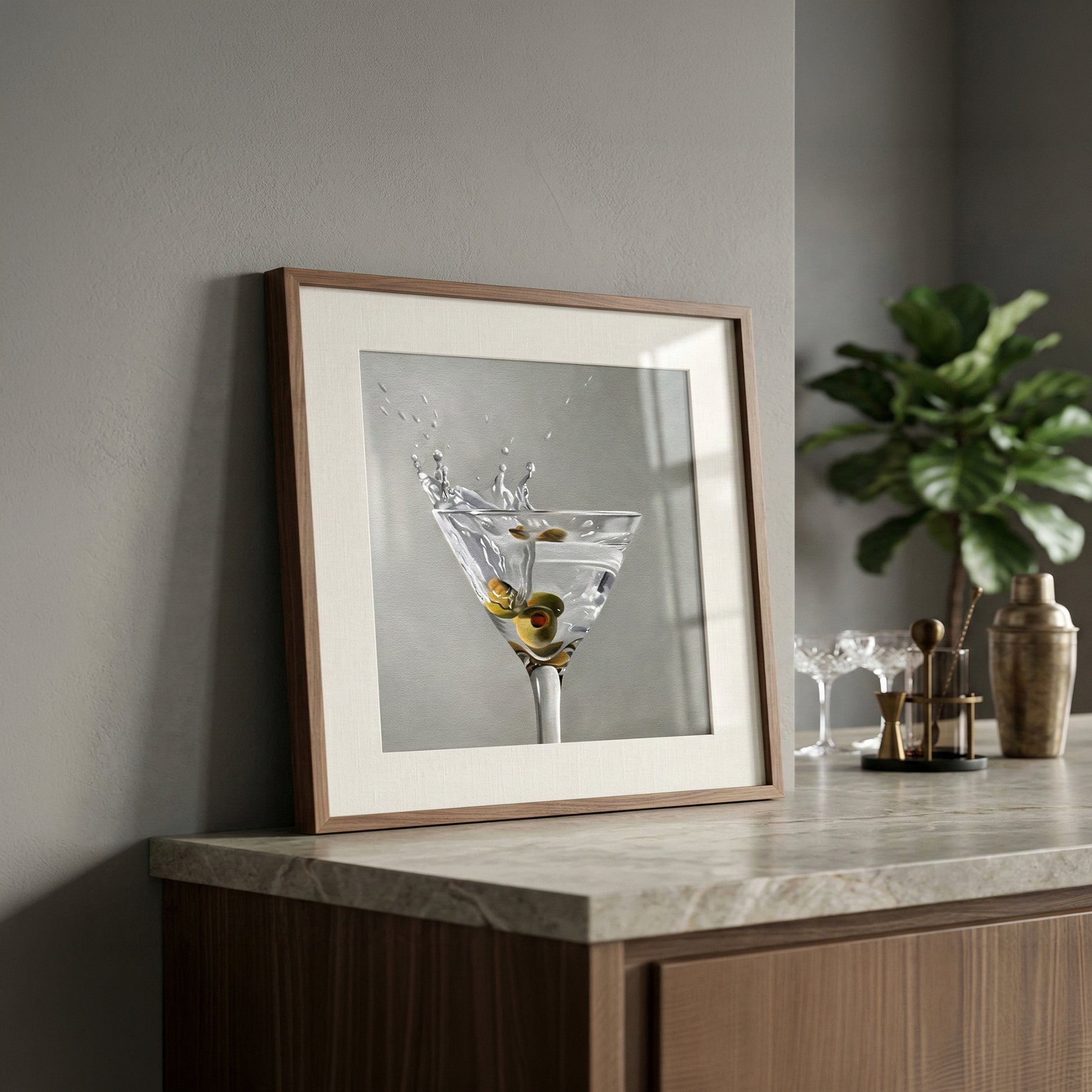 Framed fine art print of a martini glass with a splash and olives, on a marble countertop.