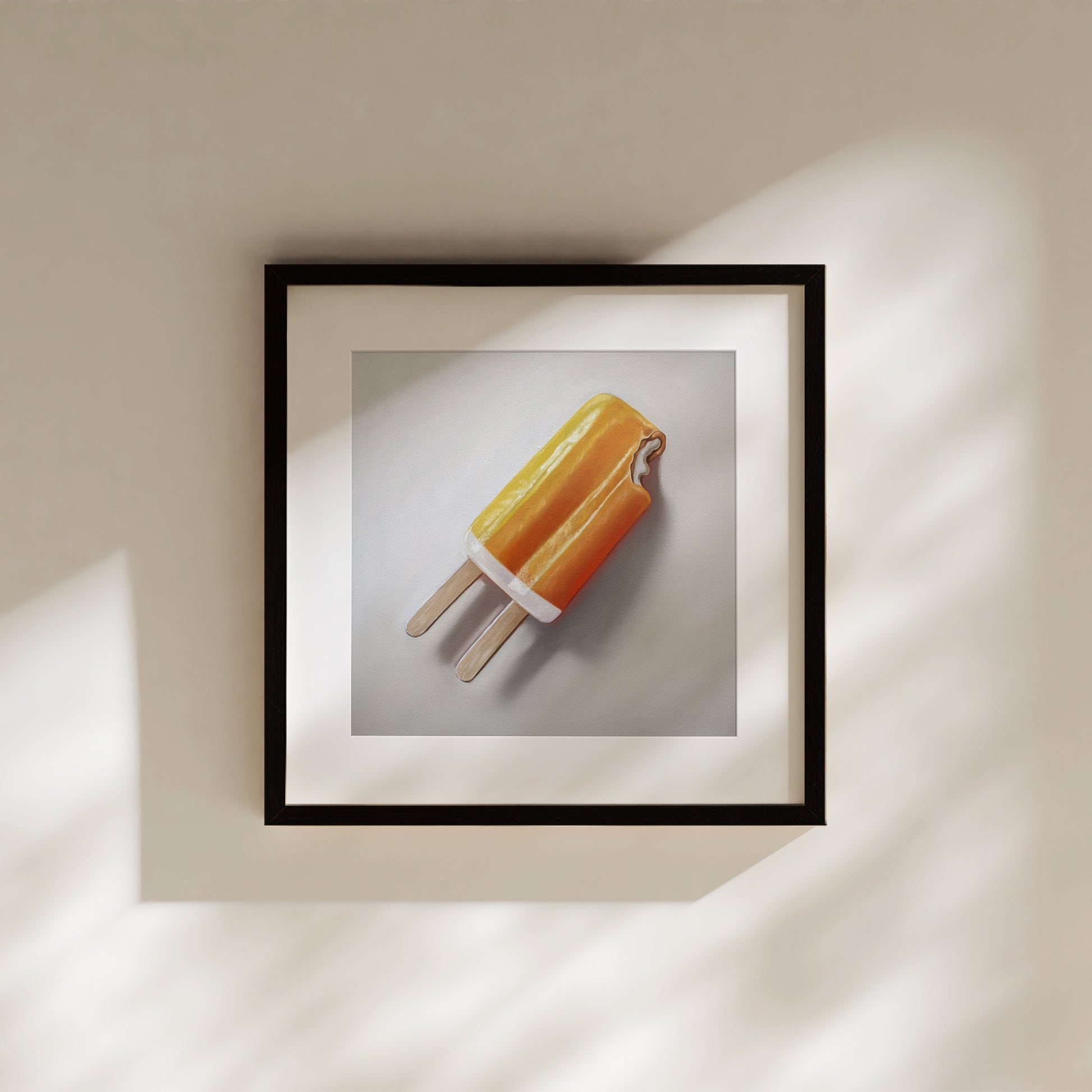 Framed fine art print of an orange dreamsicle popsicle with a bite taken out, on a light background.