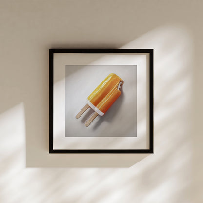 Framed fine art print of an orange dreamsicle popsicle with a bite taken out, on a light background.