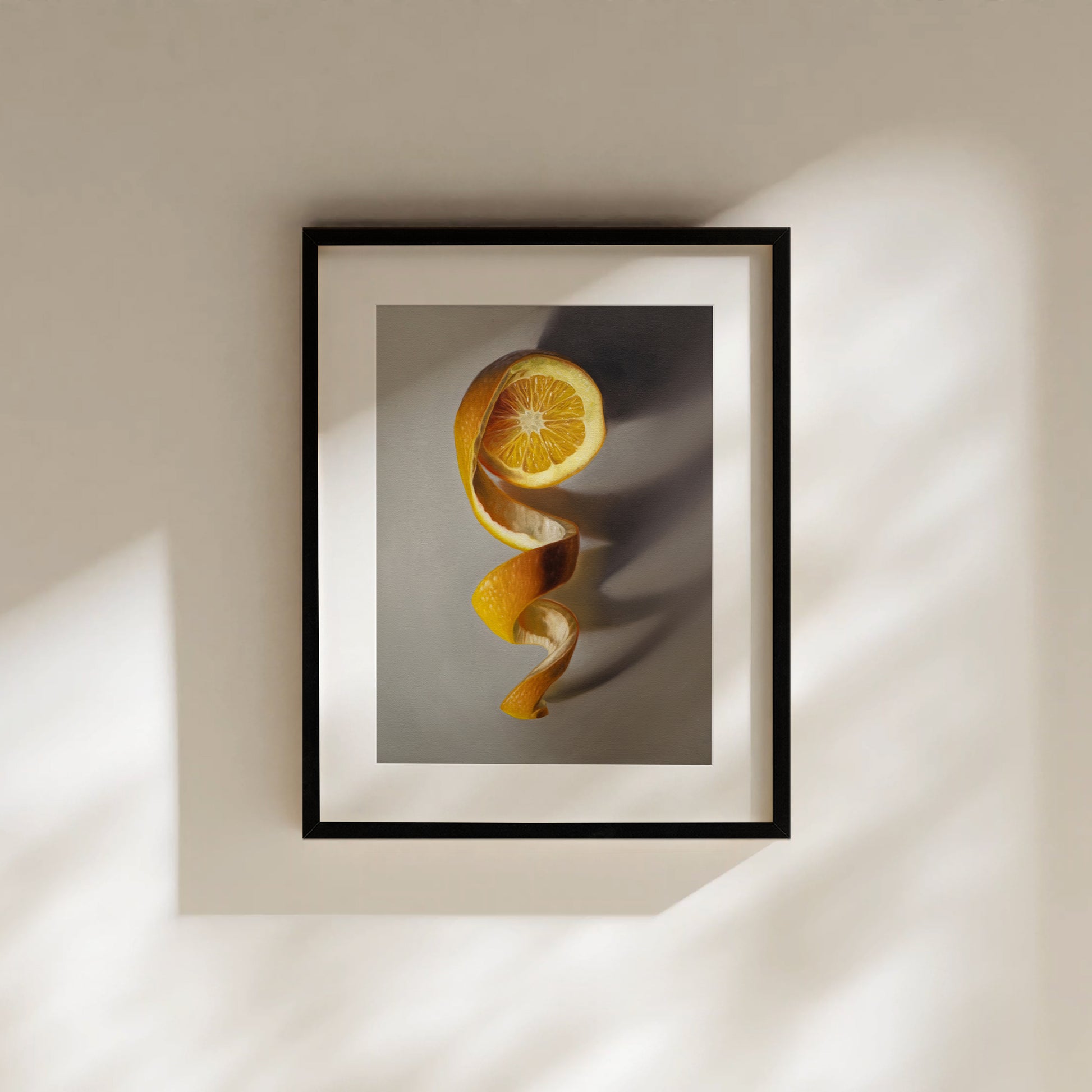 Framed "Orange Twist" fine art print featuring a vibrant orange peel spiraling down from a halved orange.
