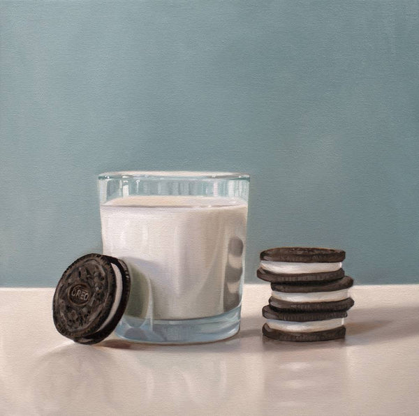 Glass of milk with a stack of Oreo cookies on a light surface against a blue background