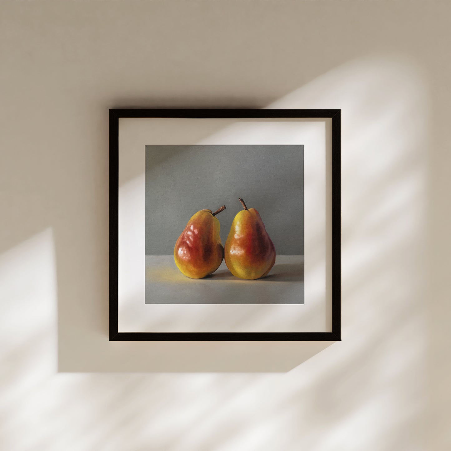 Framed fine art print of two vibrant red and yellow pears on a light surface against a gray background.