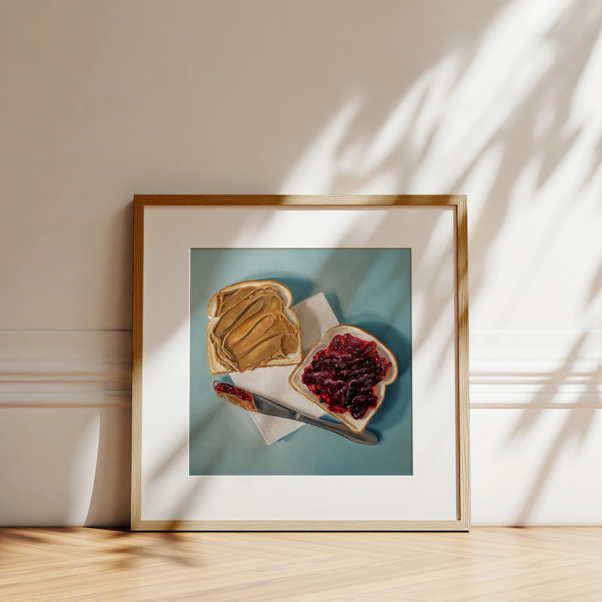 Framed fine art print of a peanut butter and jelly sandwich on a light blue background.