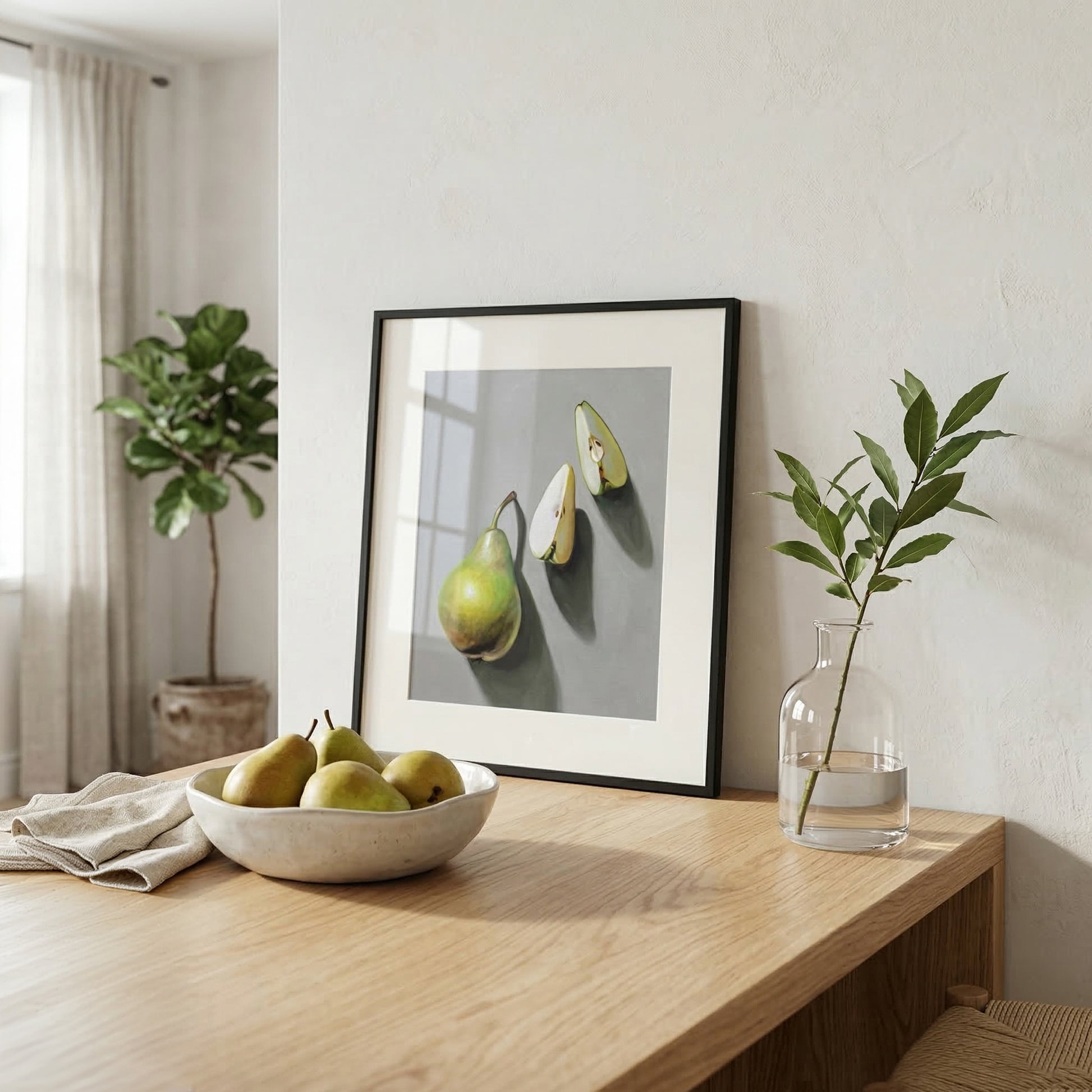 Framed "Pear Trio" fine art print with green pears on a light gray background, displayed on a wooden table.