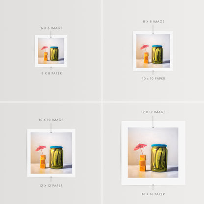 Pickles and Cheese Fine Art Print by Lauren Pretorius: a glass jar of pickles alongside a stack of cheese cubes relaxing under a drink umbrella.