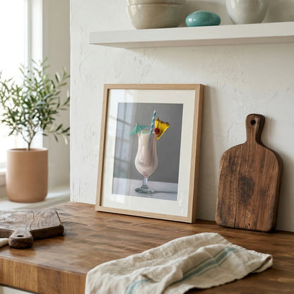 Framed Piña Colada art print with a straw, pineapple, and umbrella, displayed on a wooden counter.