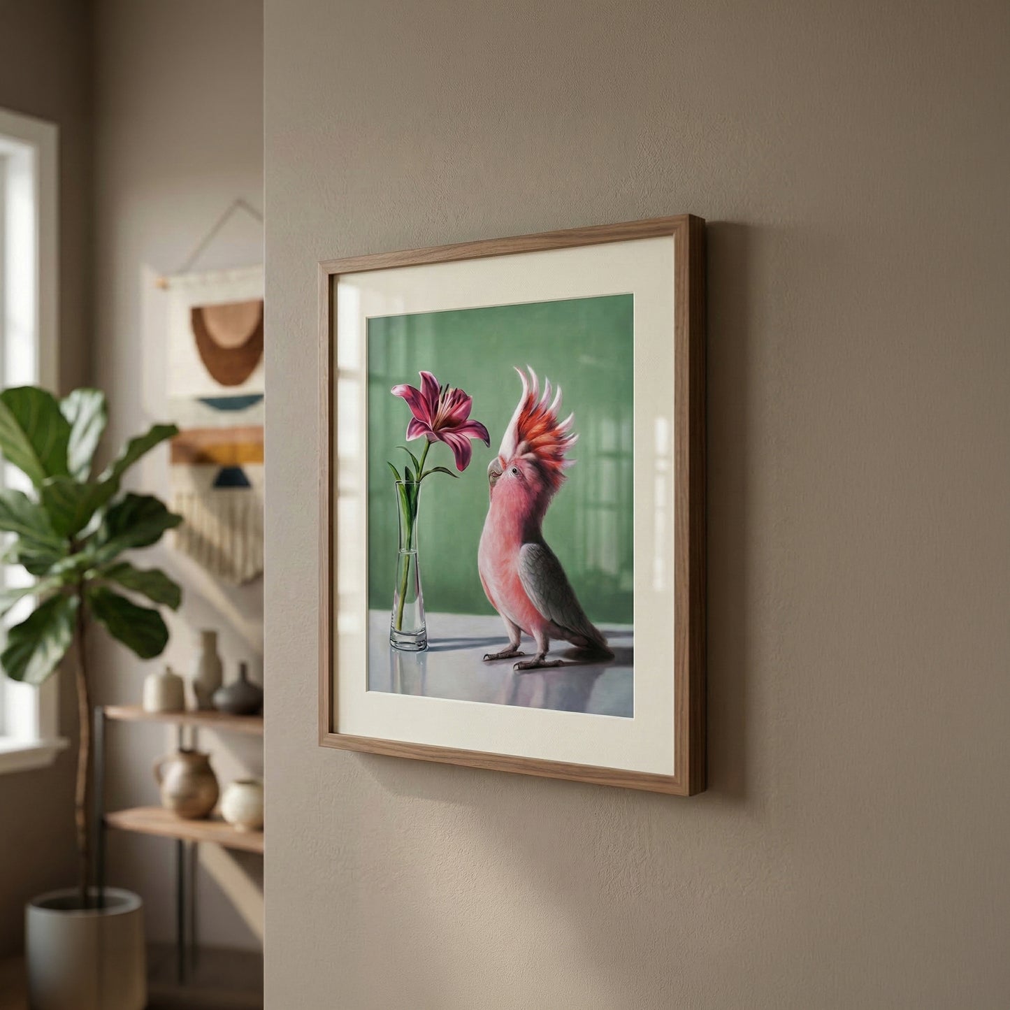 Framed art print of a pink cockatoo looking at a lily in a vase, on a green background.