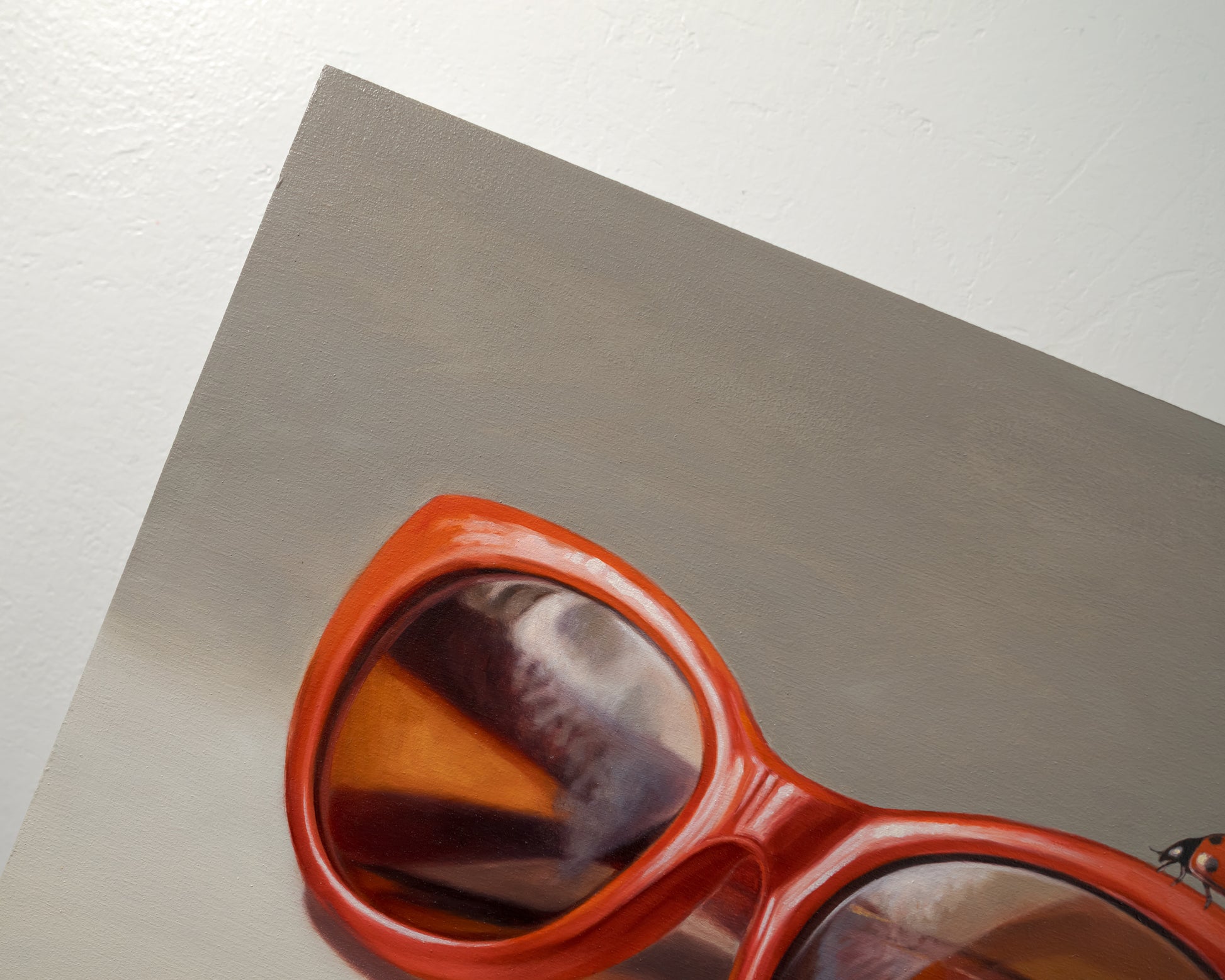 Red Ladies Trio 14" x 11" Original Oil Painting by Lauren Pretorius: red sunglasses with a reflective surface, two ladybugs on and around them against a neutral background.