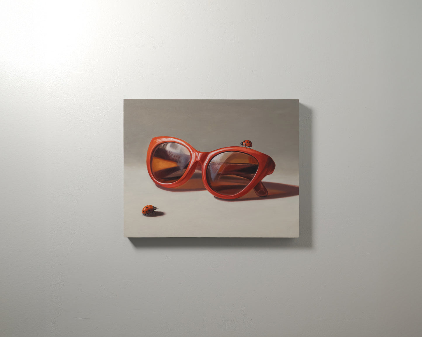 Red Ladies Trio 14" x 11" Original Oil Painting by Lauren Pretorius: red sunglasses with a reflective surface, two ladybugs on and around them against a neutral background.