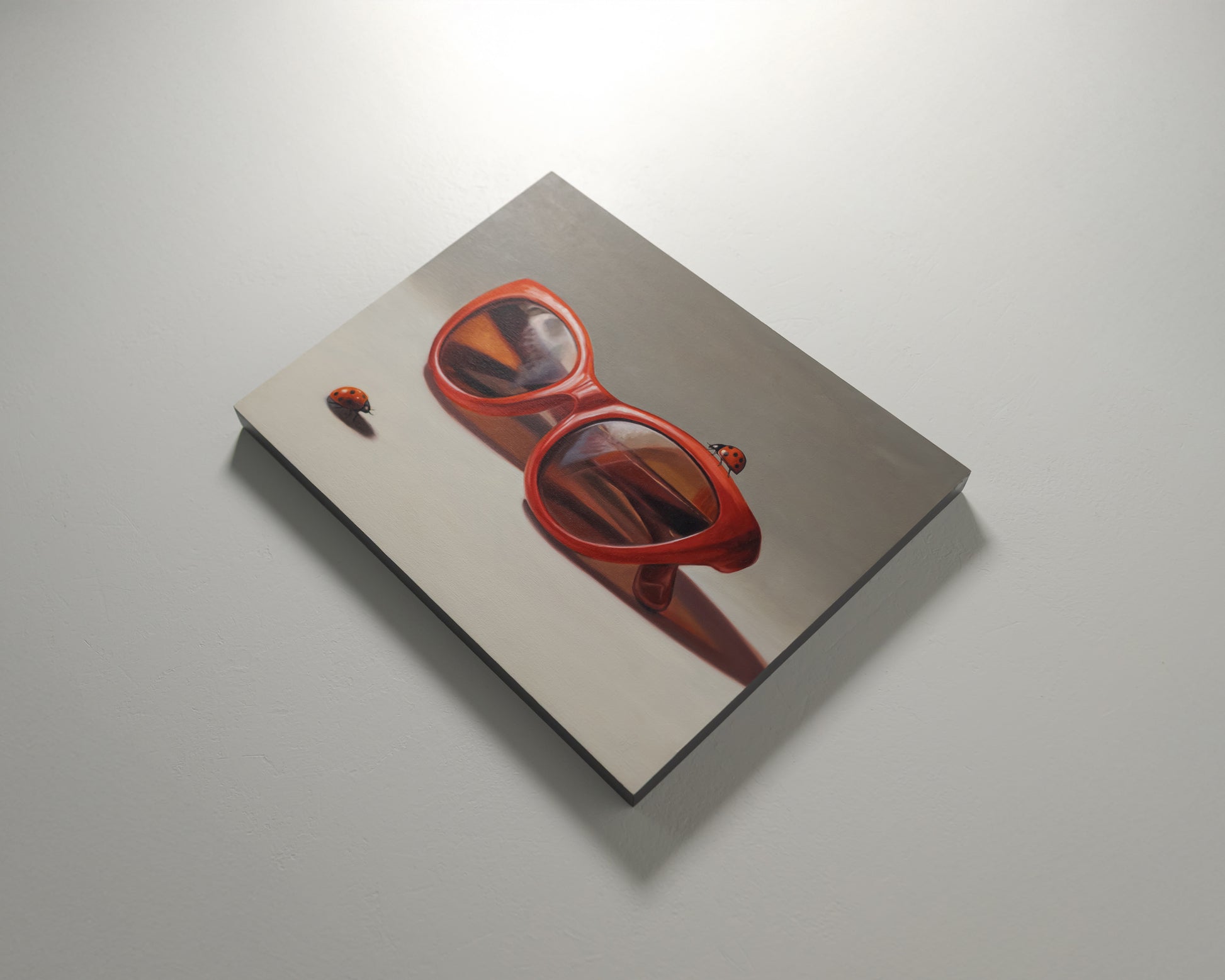 Red Ladies Trio 14" x 11" Original Oil Painting by Lauren Pretorius: red sunglasses with a reflective surface, two ladybugs on and around them against a neutral background.