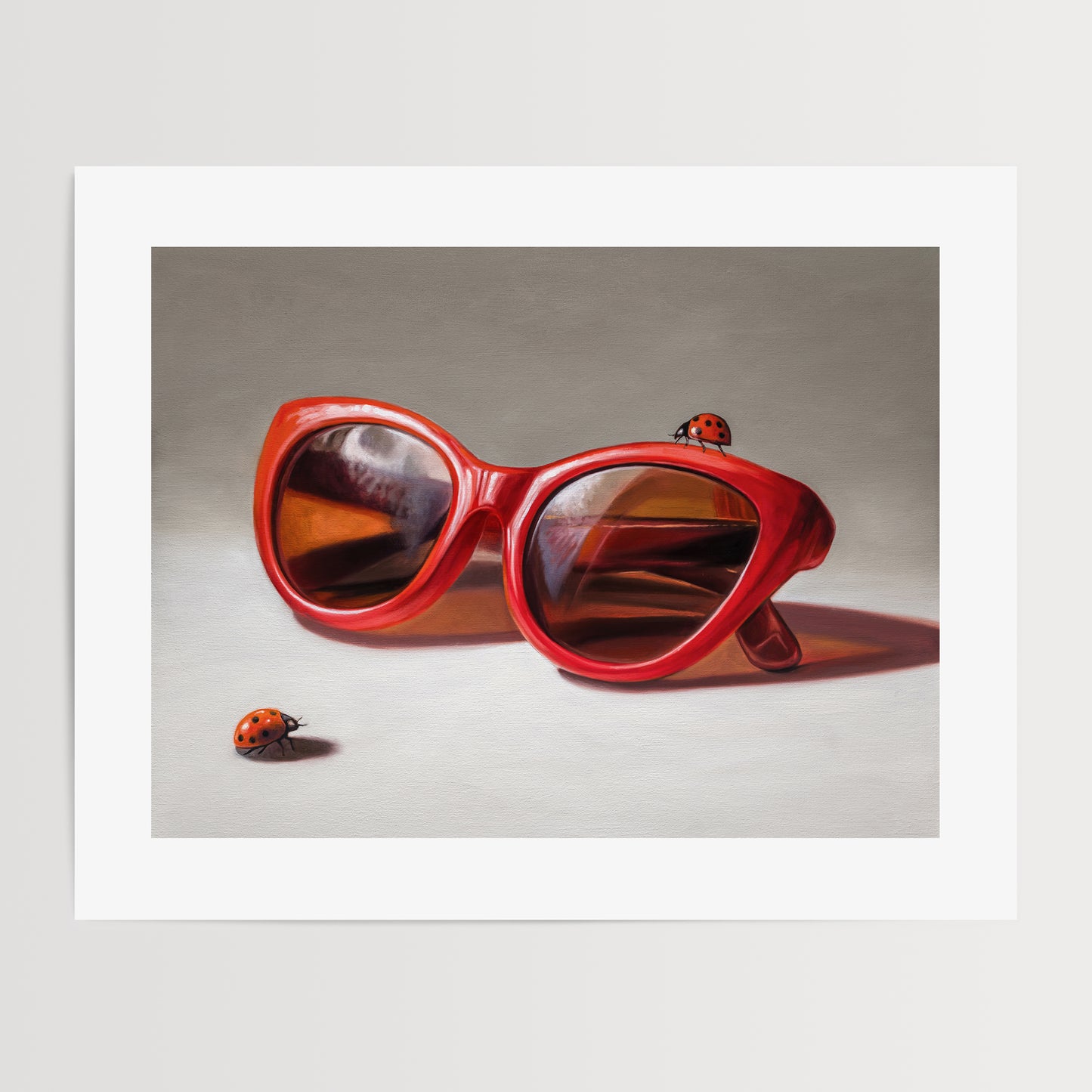 Red Ladies Trio Fine Art Print by Lauren Pretorius: red sunglasses with a reflective surface, two ladybugs on and around them against a neutral background.