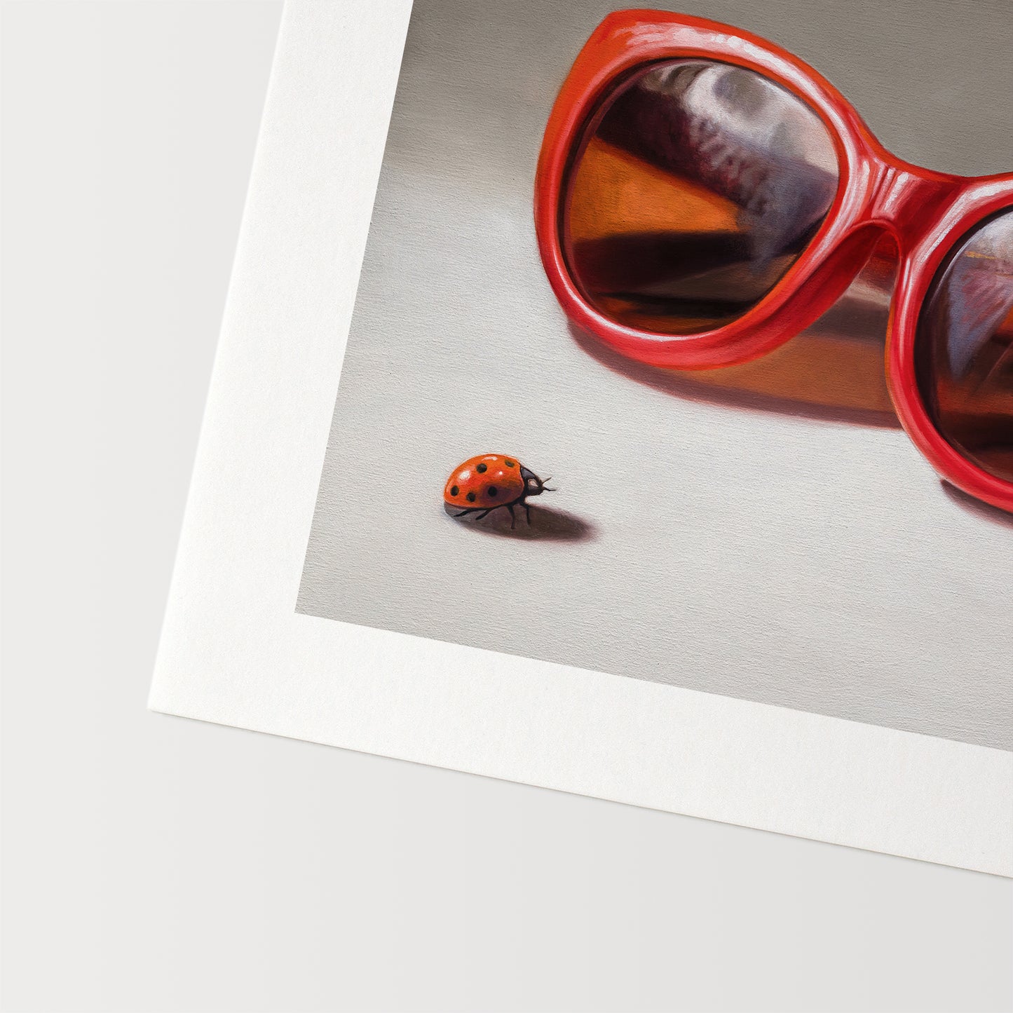 Red Ladies Trio Fine Art Print by Lauren Pretorius: red sunglasses with a reflective surface, two ladybugs on and around them against a neutral background.