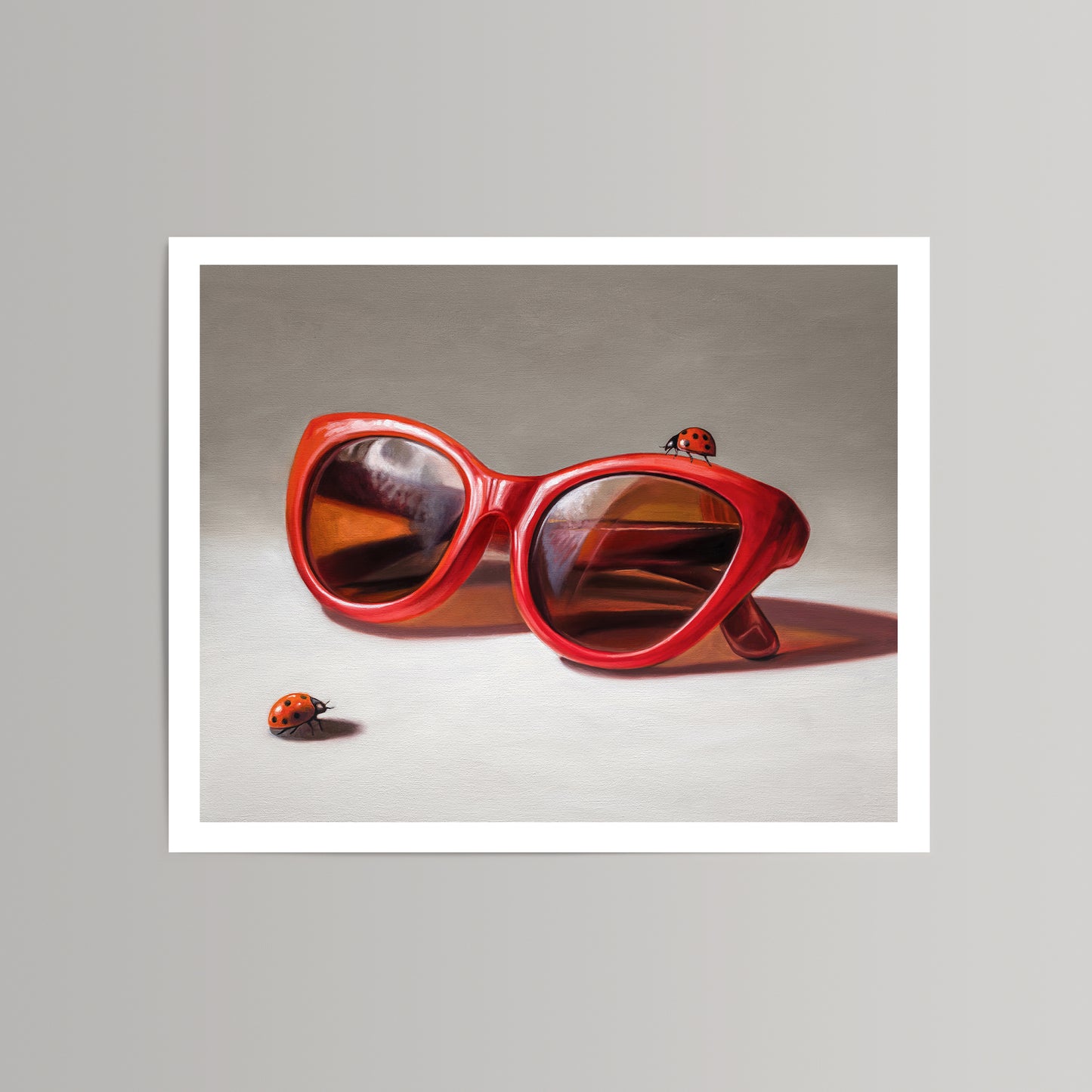 Vibrant red cat-eye sunglasses with reflective lenses and two ladybugs on a neutral background fine art print.