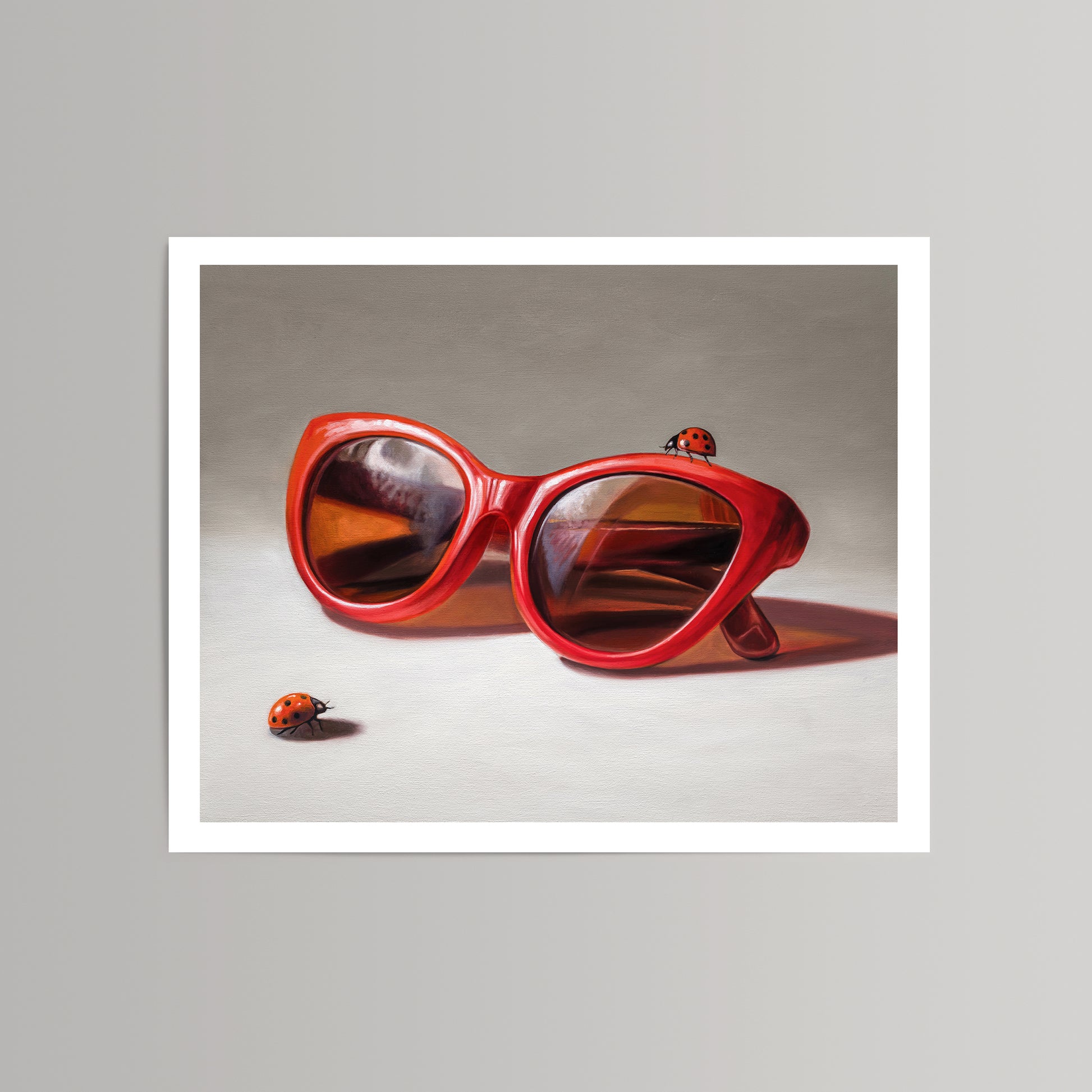 Vibrant red cat-eye sunglasses with reflective lenses and two ladybugs on a neutral background fine art print.