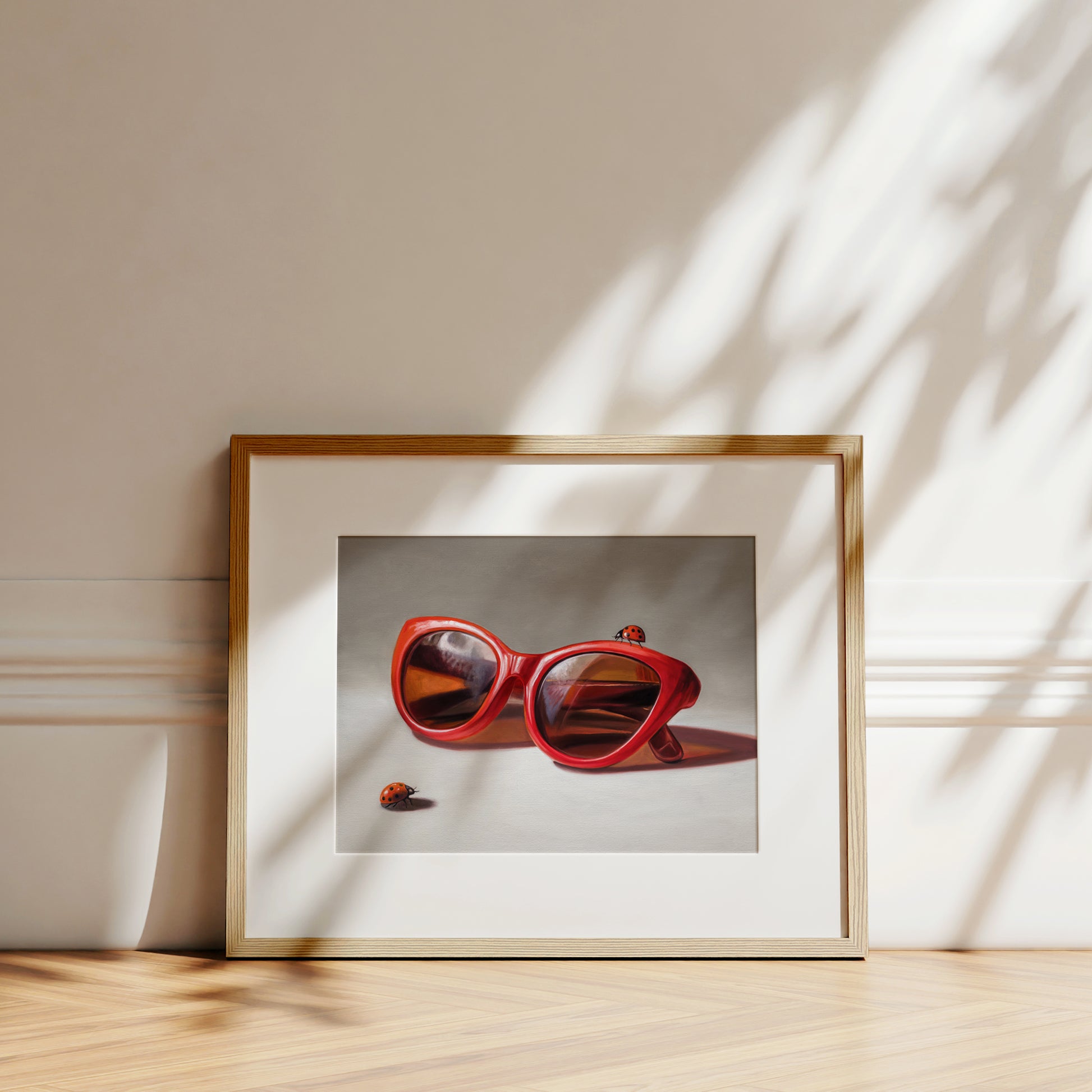 Framed "Red Ladies Trio" fine art print featuring red cat-eye sunglasses and two ladybugs on museum-grade paper.