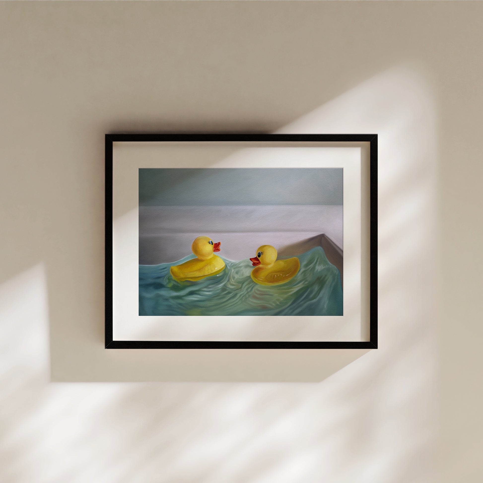 Framed fine art print of two yellow rubber ducks in blue wavy water, with a light background.