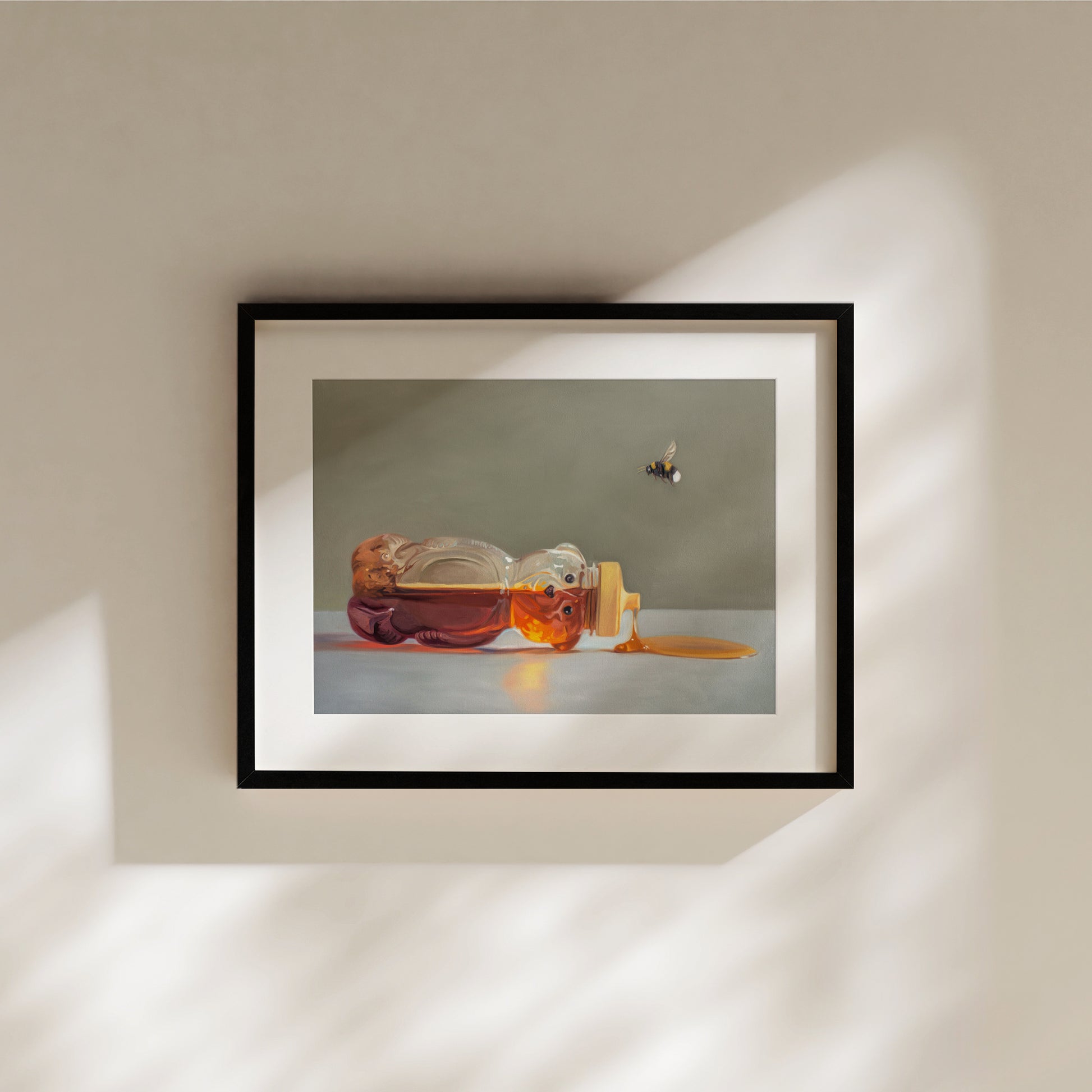 Spilled Honey and Bumble Bee Fine Art Print by Lauren Pretorius: a classic honey bear bottle tipped on its side spilling its contents while a bumble bee hovers above.