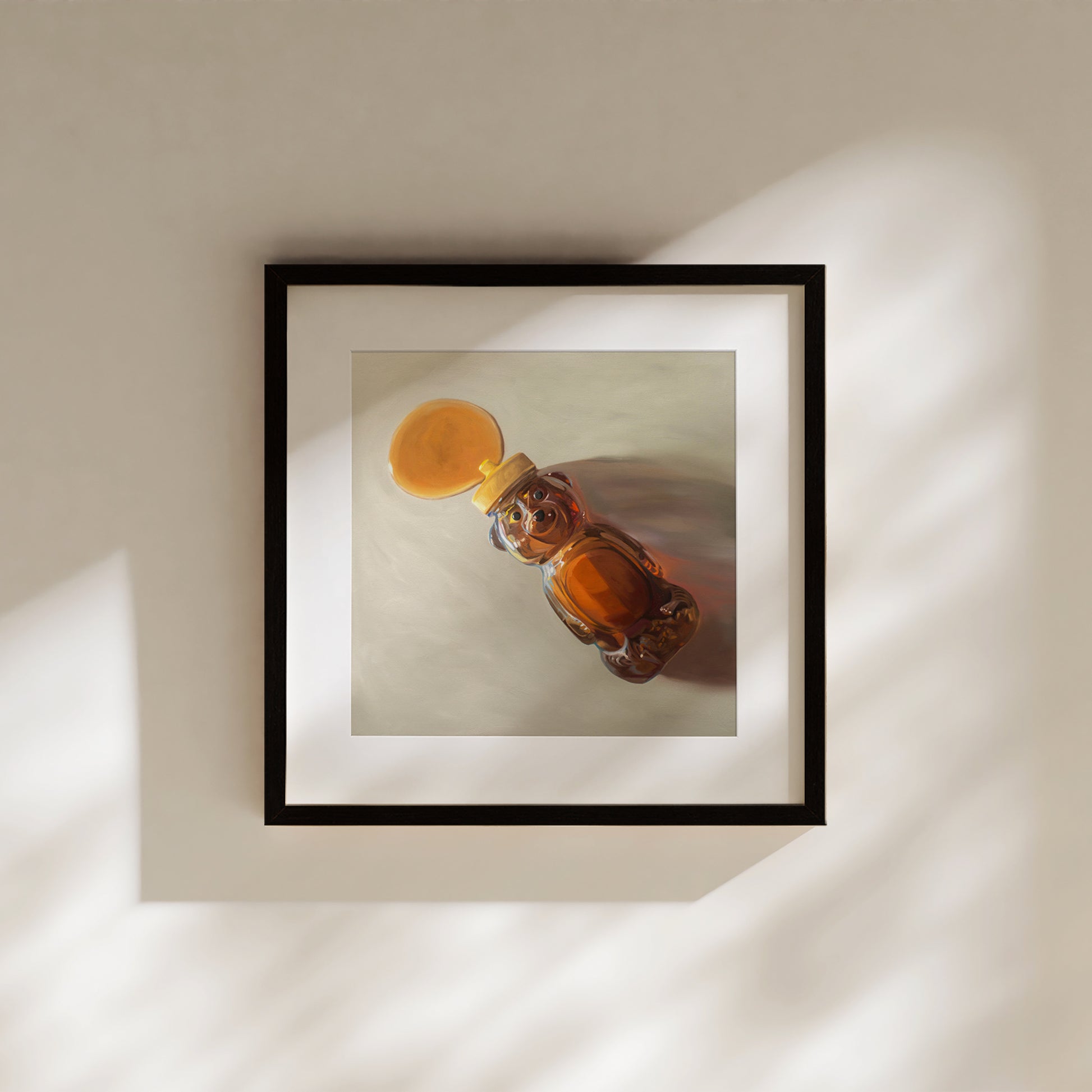 Framed fine art print of a honey bear bottle spilling golden honey, with warm light and shadows.