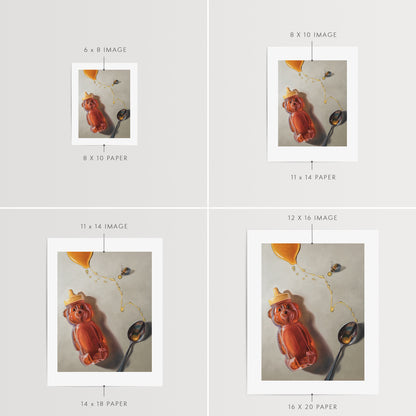 Spilled Honey, Spoon & Bee Fine Art Print by Lauren Pretorius: a bear-shaped honey container, a spoon, and a bee with spilled honey elements, printed on matte archival fine art paper.