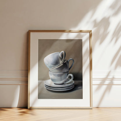 Framed fine art print of two stacked white ceramic cups and saucers, with soft shadows.
